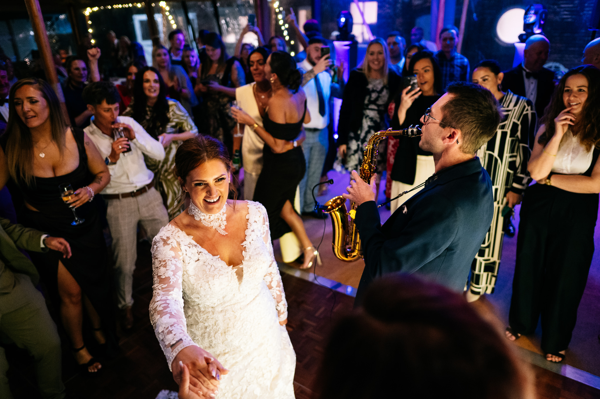 a smiling bride dancing next to a wedding saxophonist