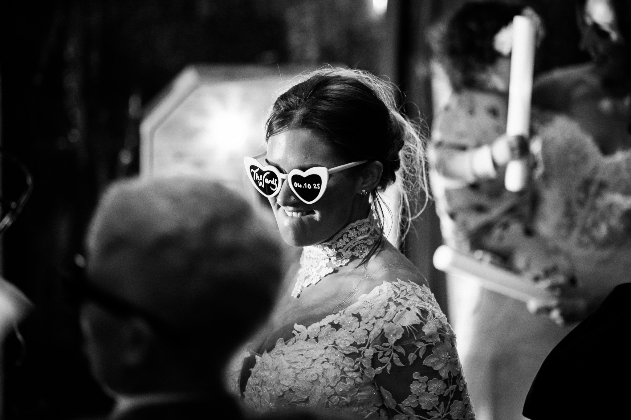 a bride on the dancefloor wearing heart shaped sunglasses with their wedding date written on the lenses