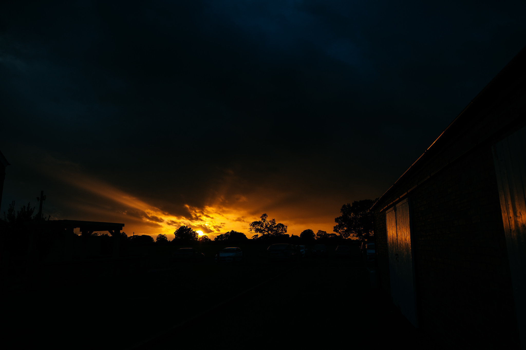 an orange sunset with the silhouette of trees in the distance