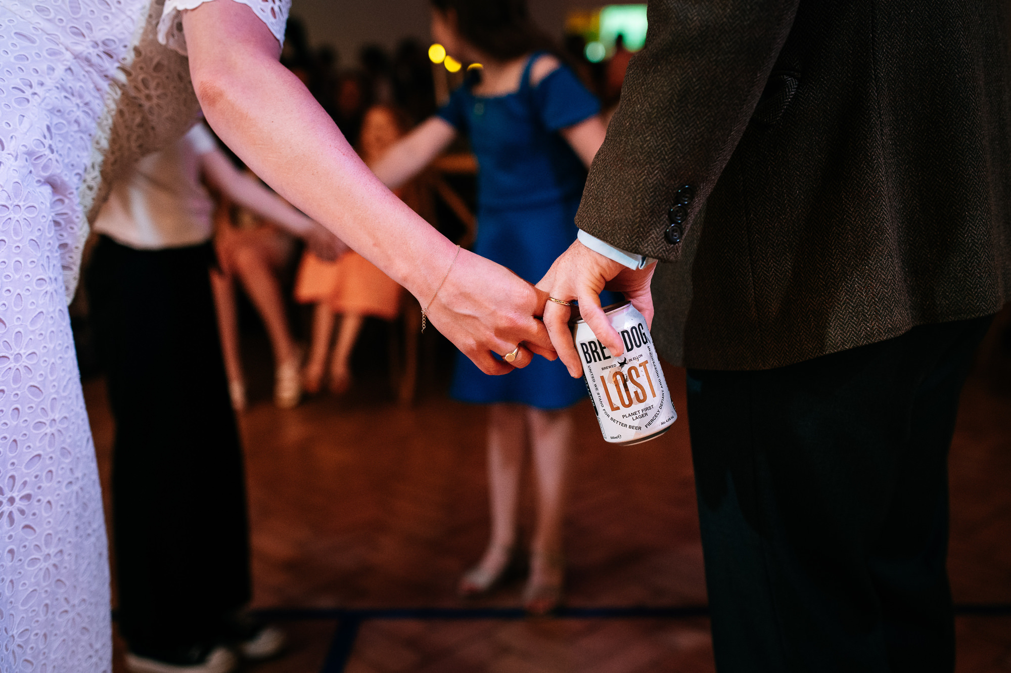 bride and groom holding hands over a can of lager