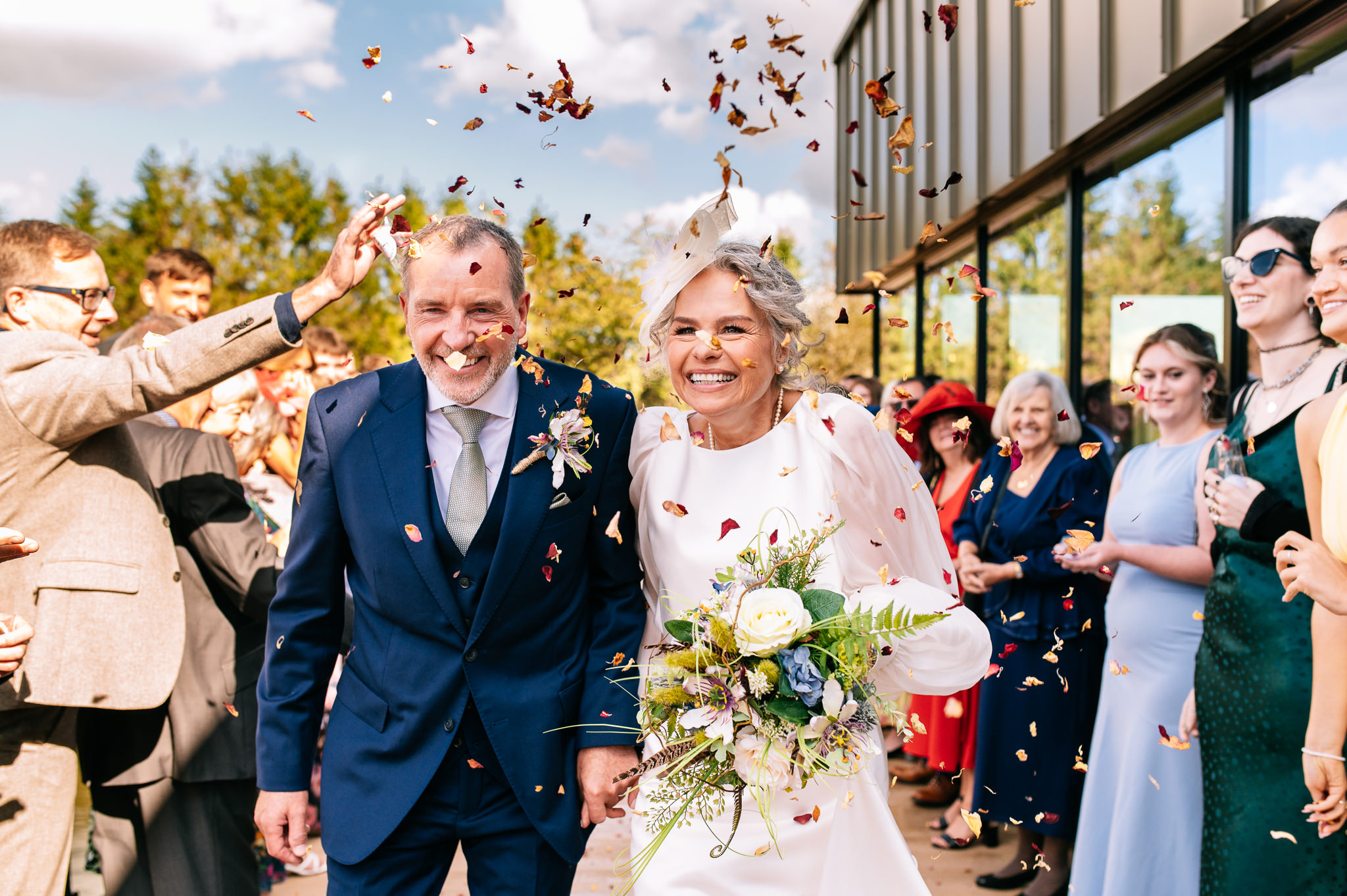 newlyweds walking through a confetti tunnel outdoors at whistle barns in Derbyshire