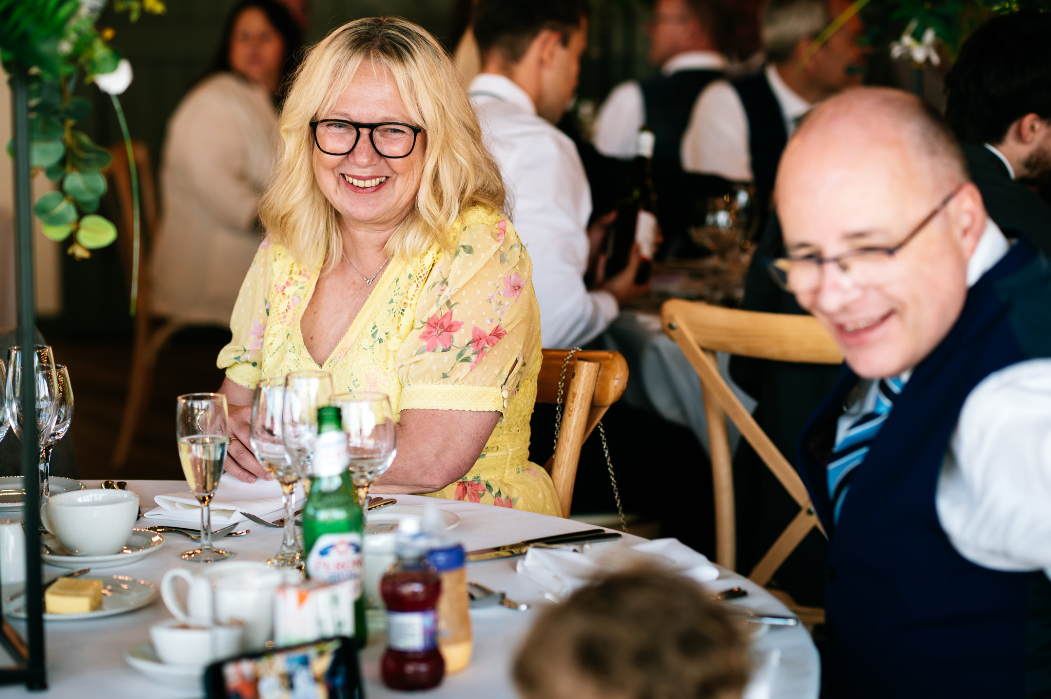 a lady with blonde hair and a yellow dress smiling across the table at a young boy