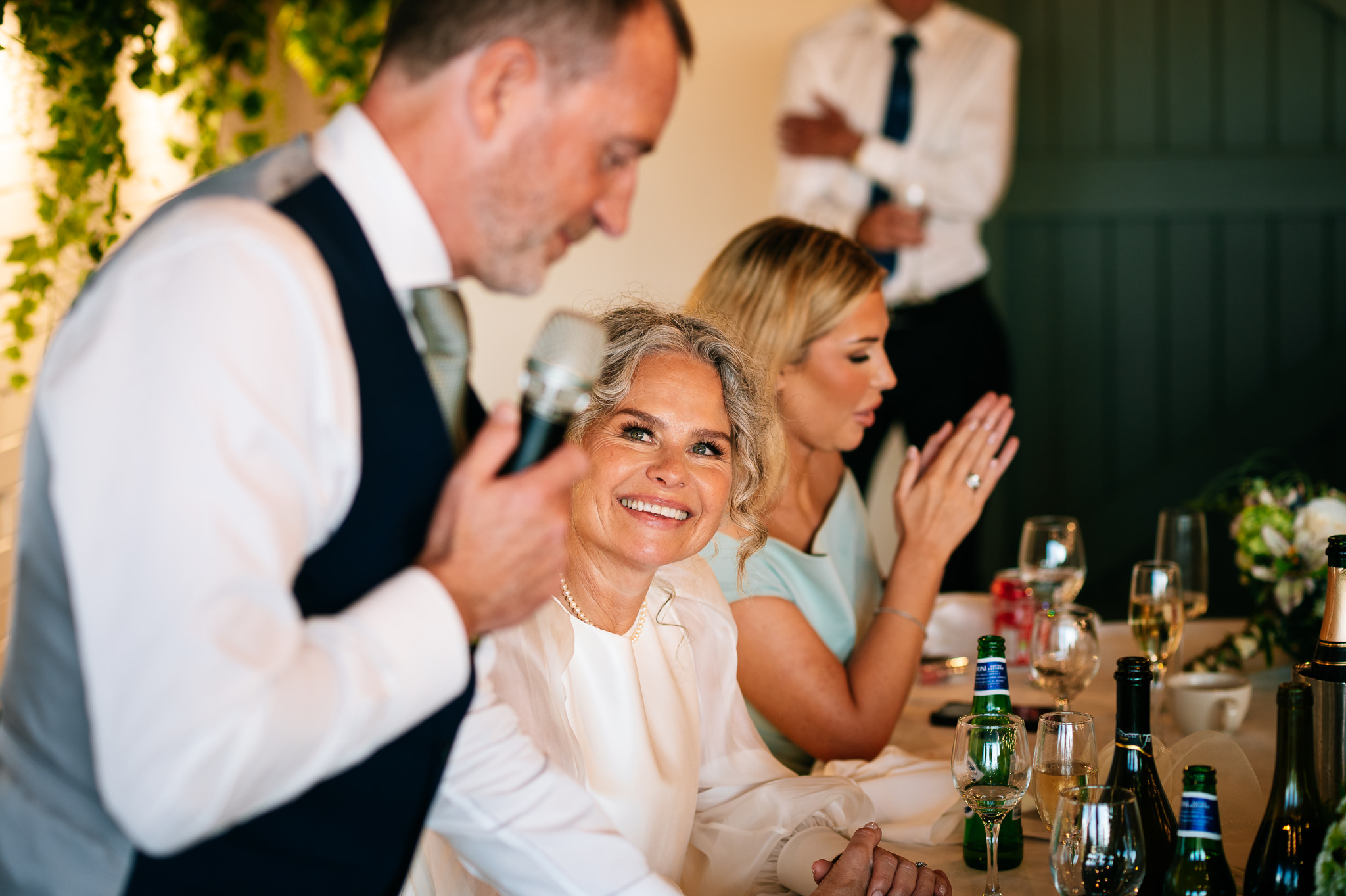 smiling bride looking up at her husband as he gives his speech