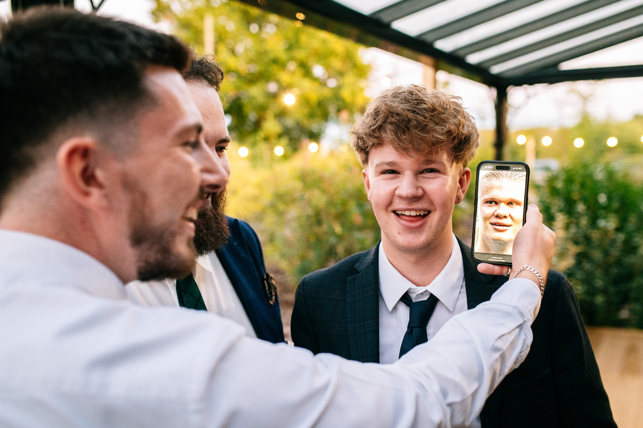 man holding up a phone with a photo of erling haaland next to another man's face