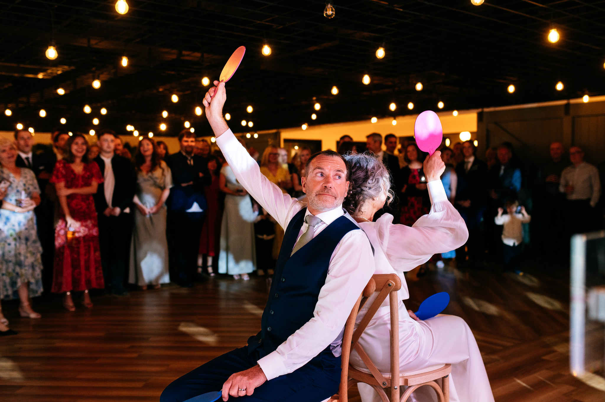 bride and groom playing the him and her game with table tennis paddles
