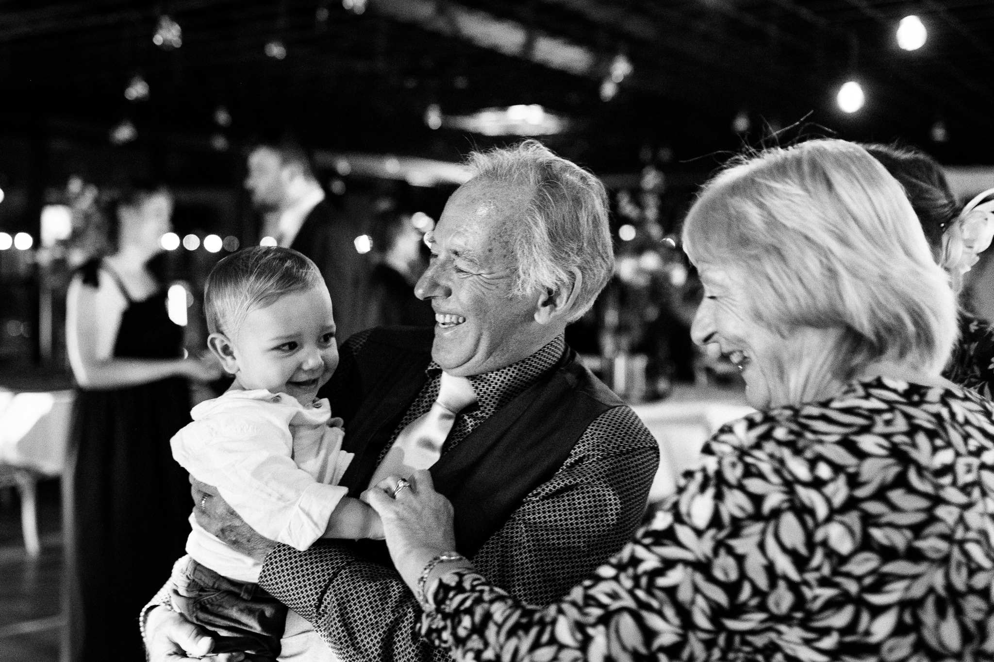 an older man and woman holding and dancing with a toddler