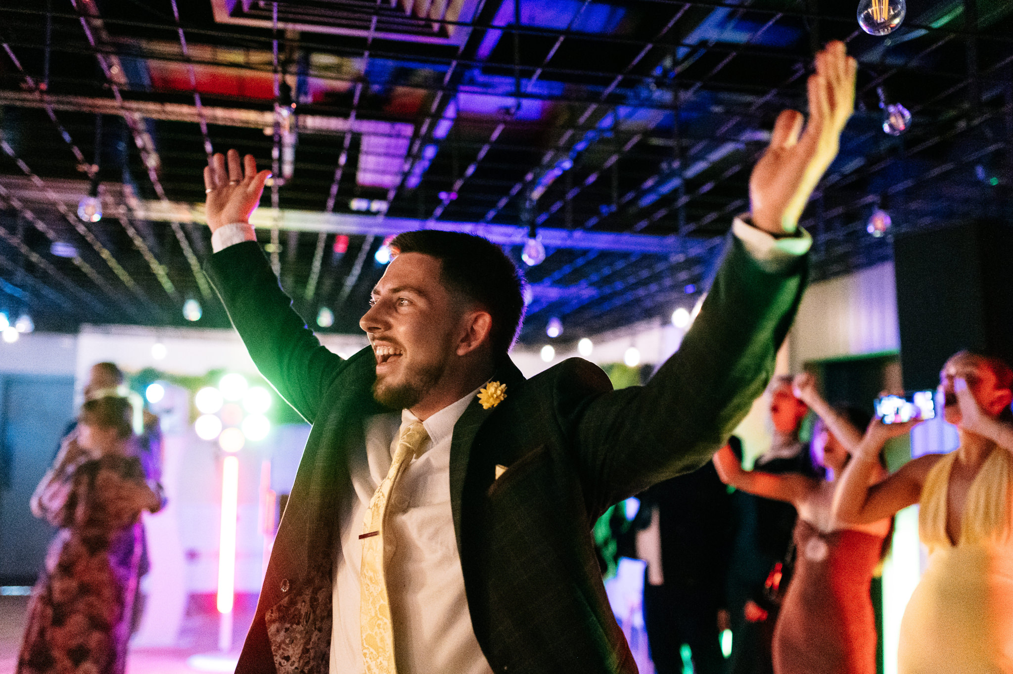 man on the dancefloor at a wedding with his arms in the air