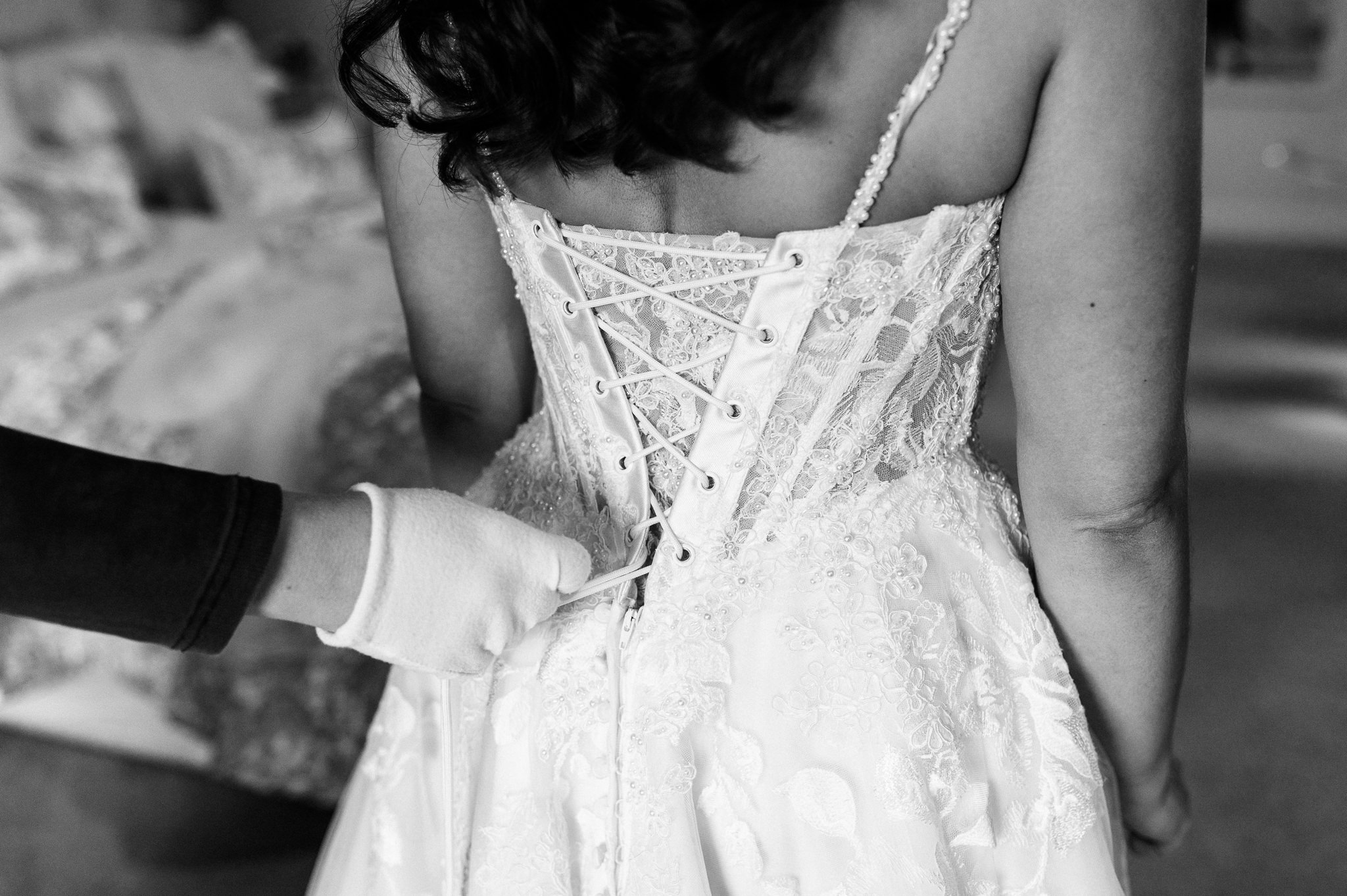 black and white photo of the bride having her dress laced up