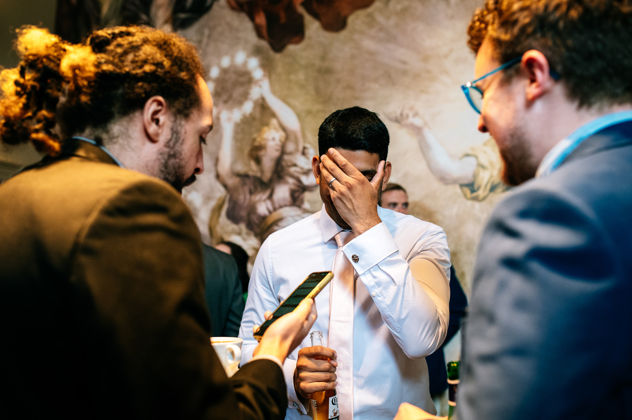 wedding guest in a white shirt with his head in his hands