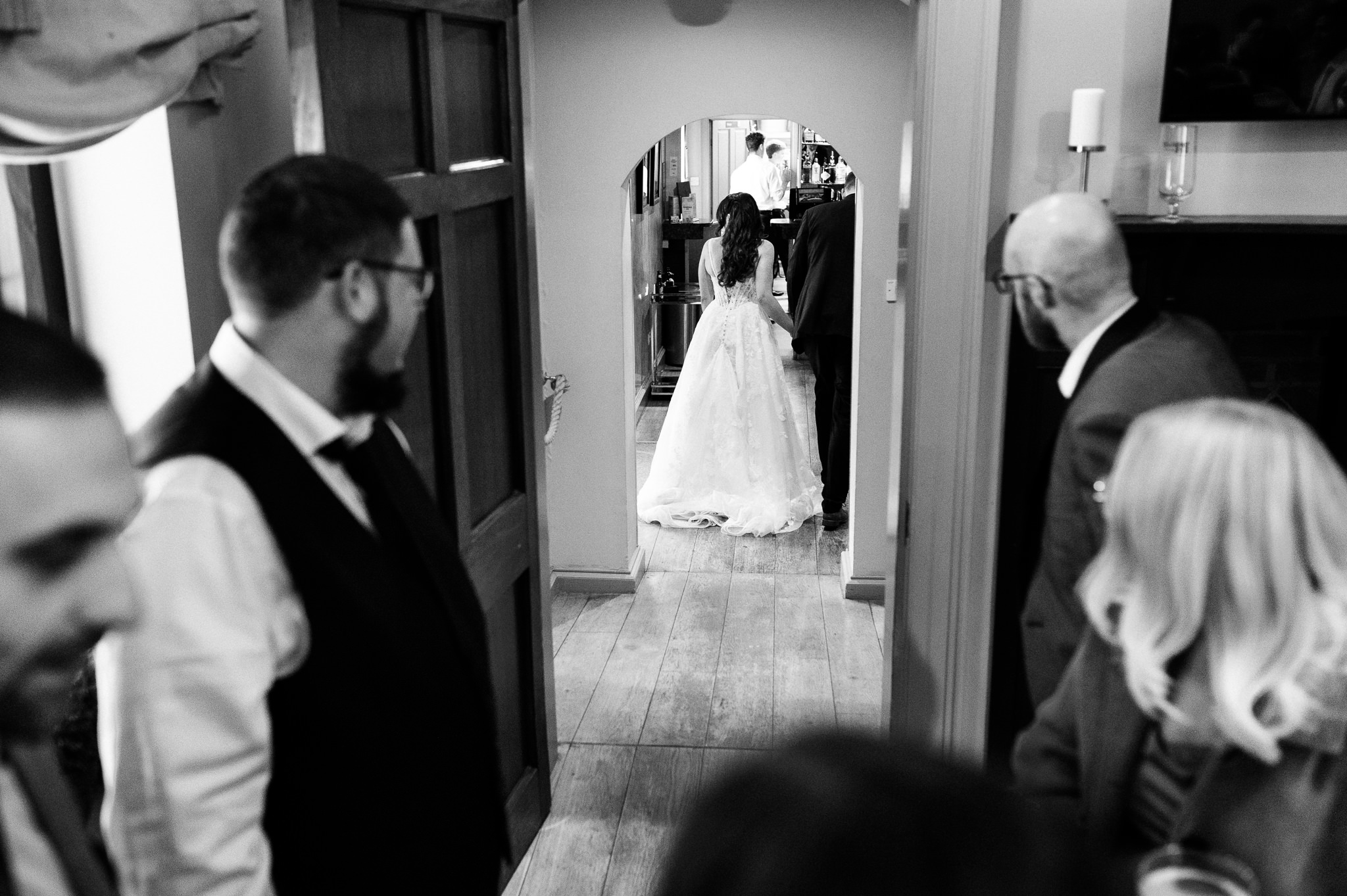 black and white photo of guests watching the bride and groom leave a room