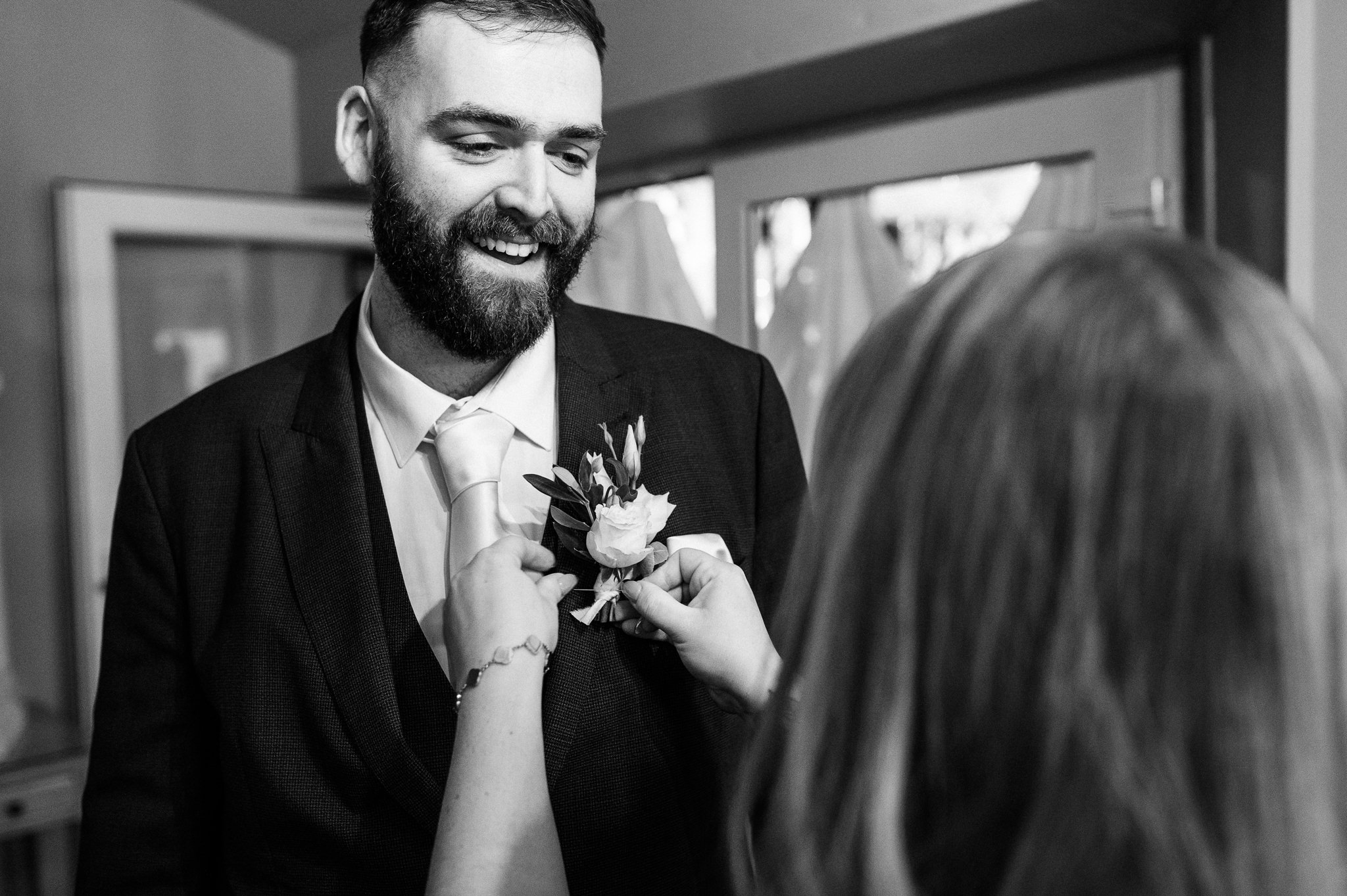 black and white photo of the best man having his button hole attached