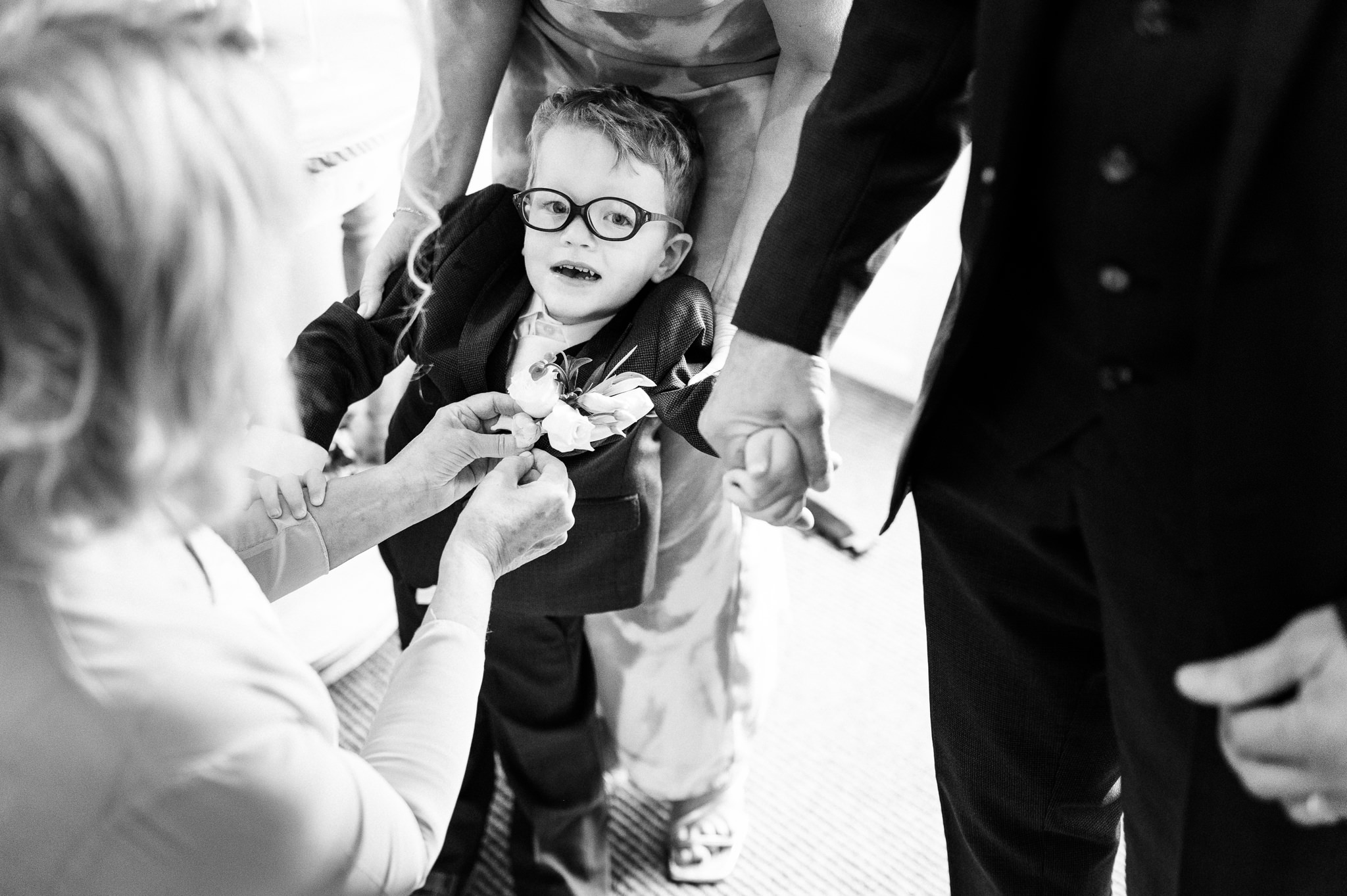 black and white photo of the page boy being dressed and having his button hole attached