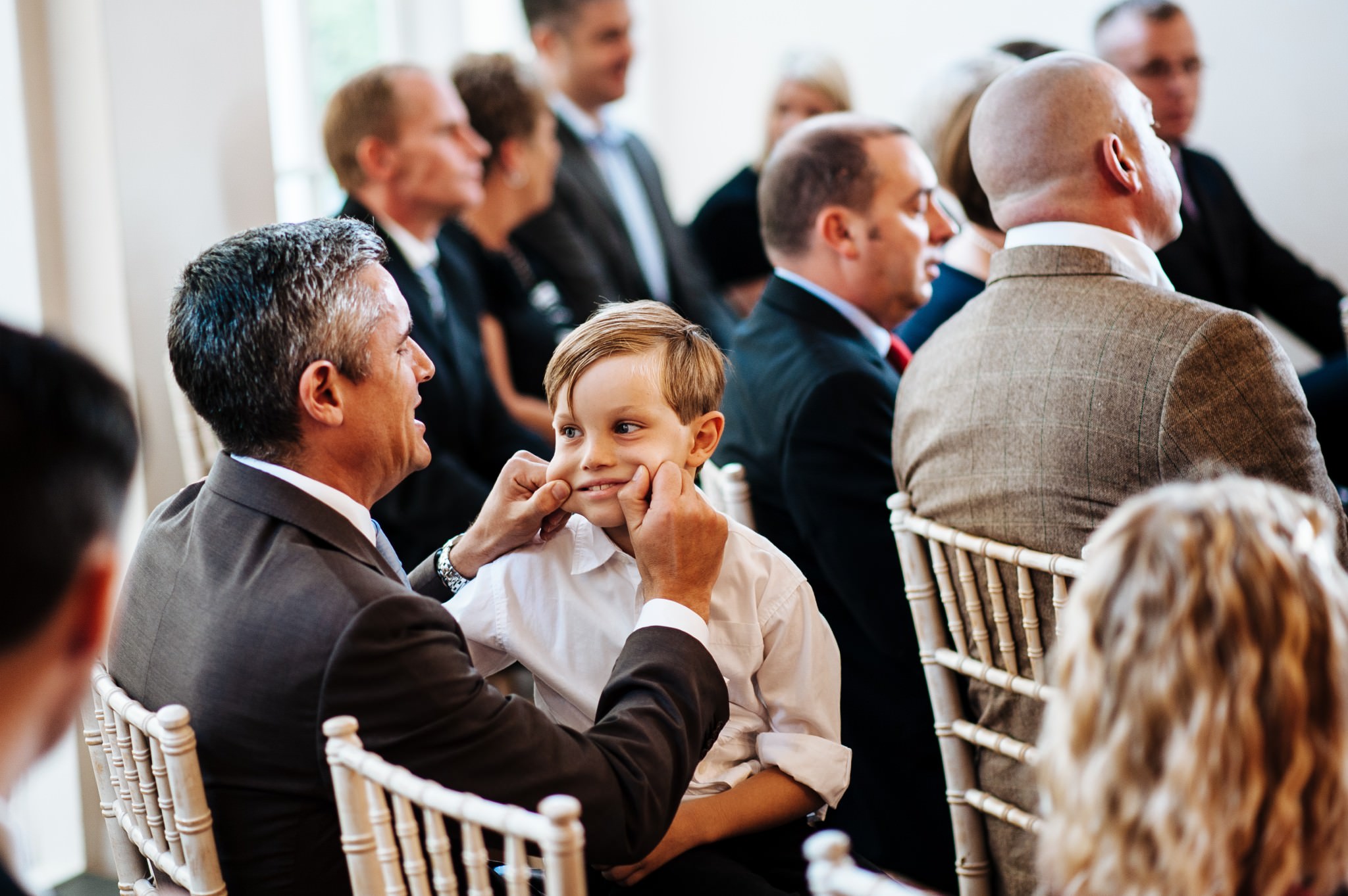 a man pinching a boys cheeks during a wedding ceremony