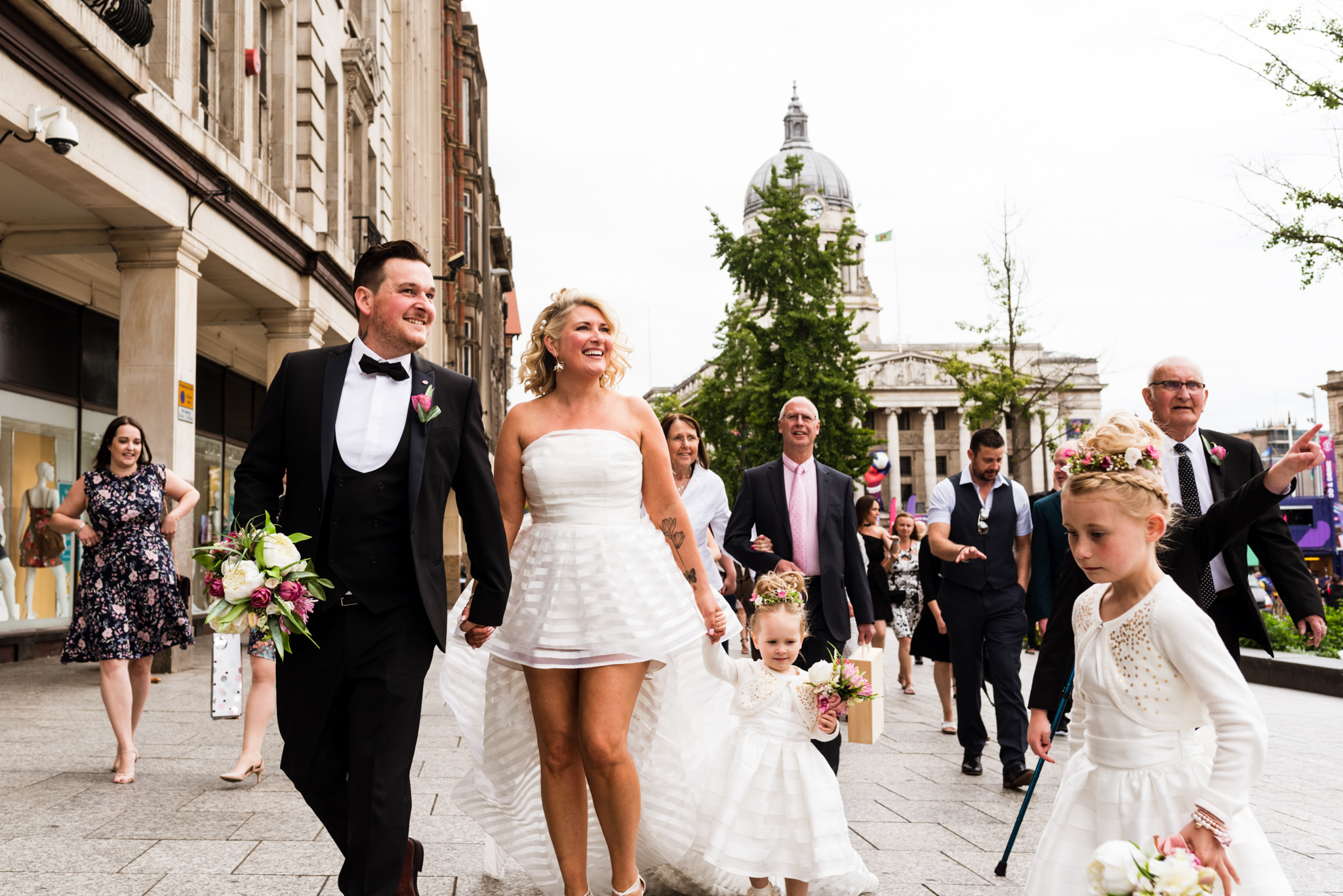 bride and groom walking with a small wedding party through a city 