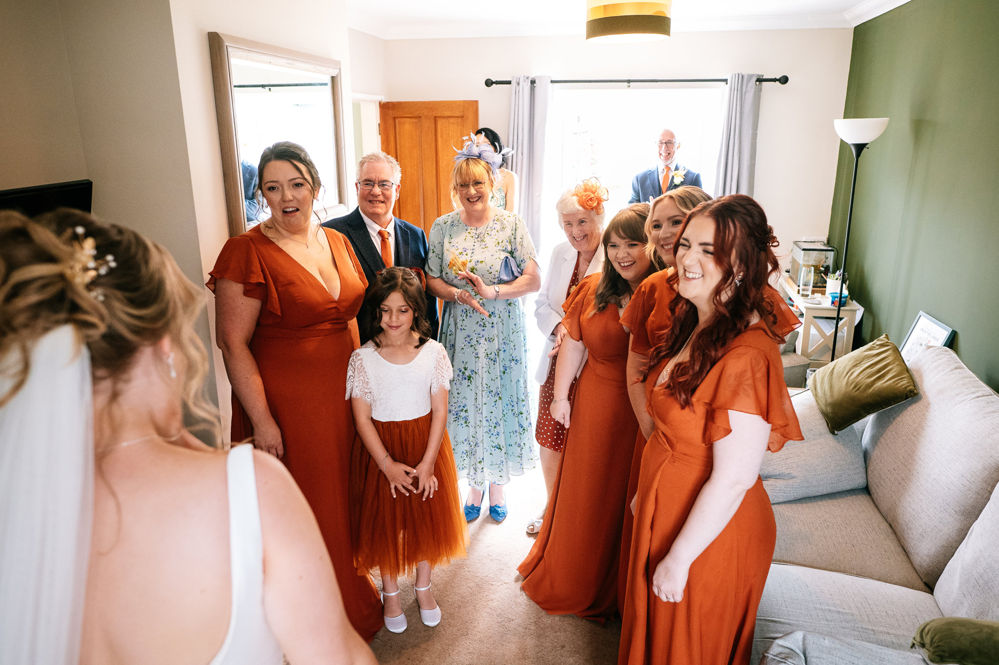 bridesmaids in burnt orange dresses smiling at the bride