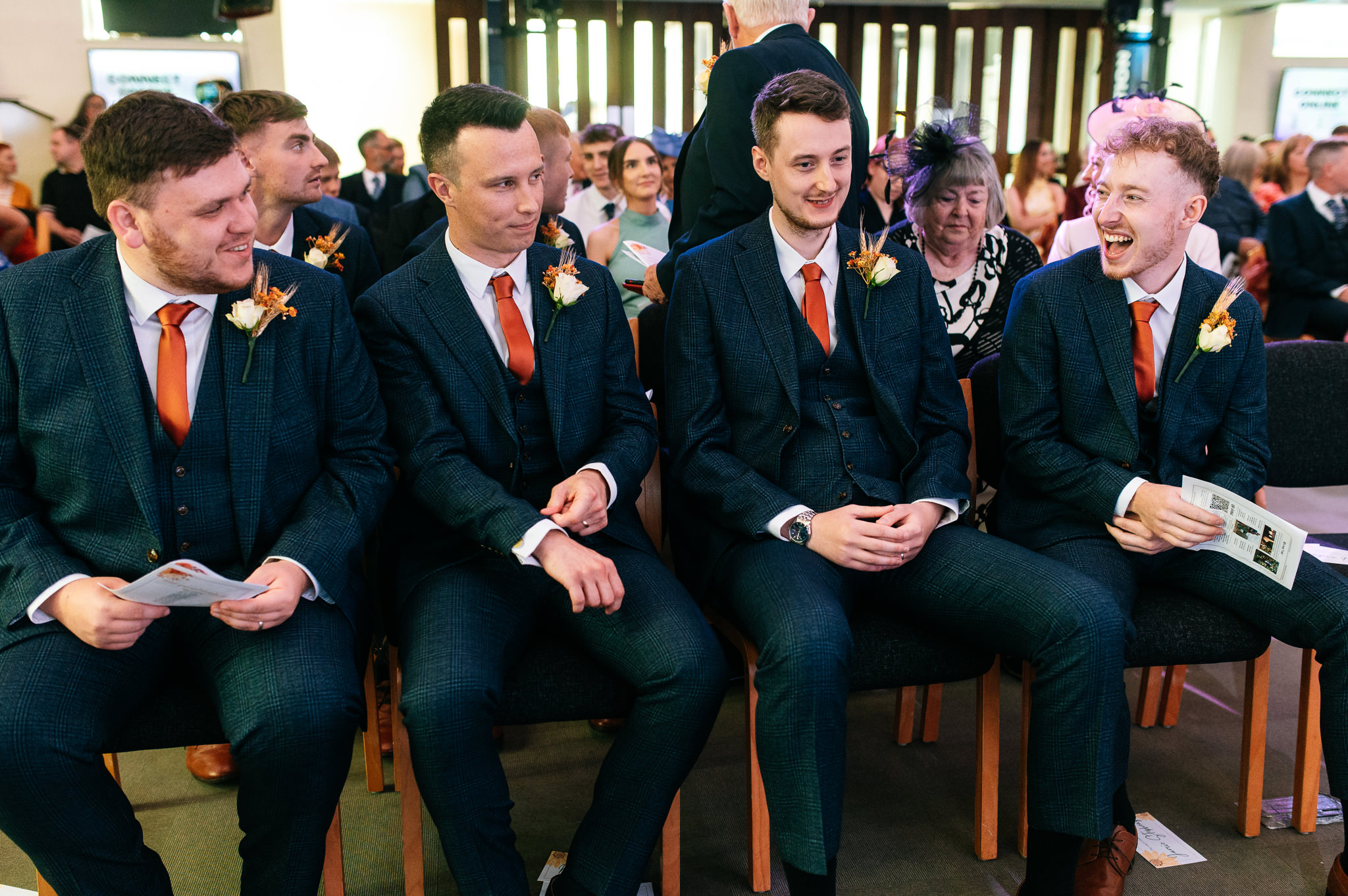 groom sharing a laugh with his groomsmen as they sit down waiting for the bride to arrive
