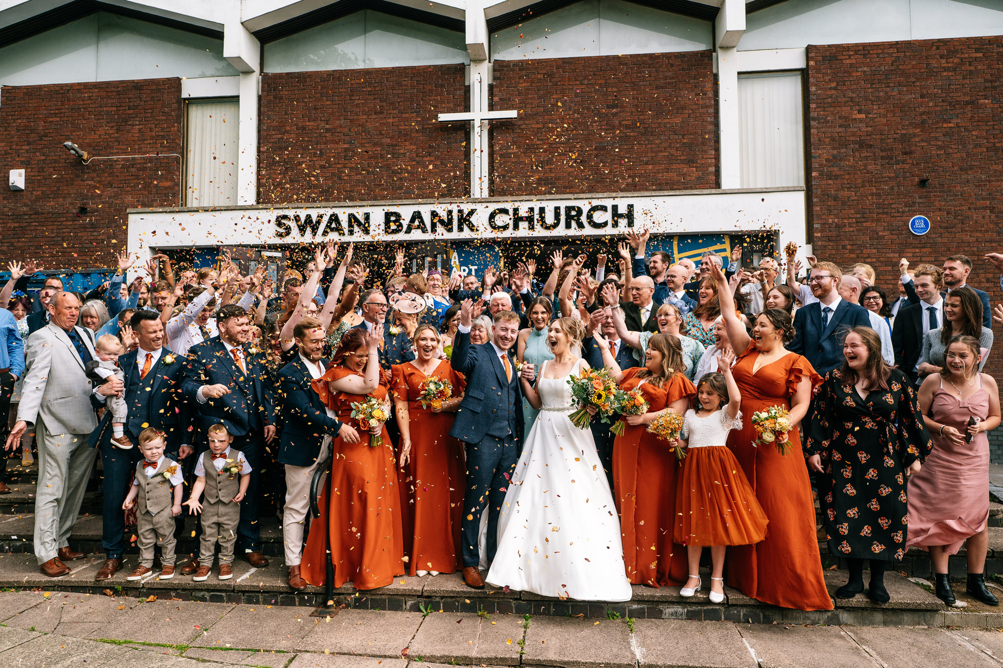 big confetti group shot in front of swan bank church