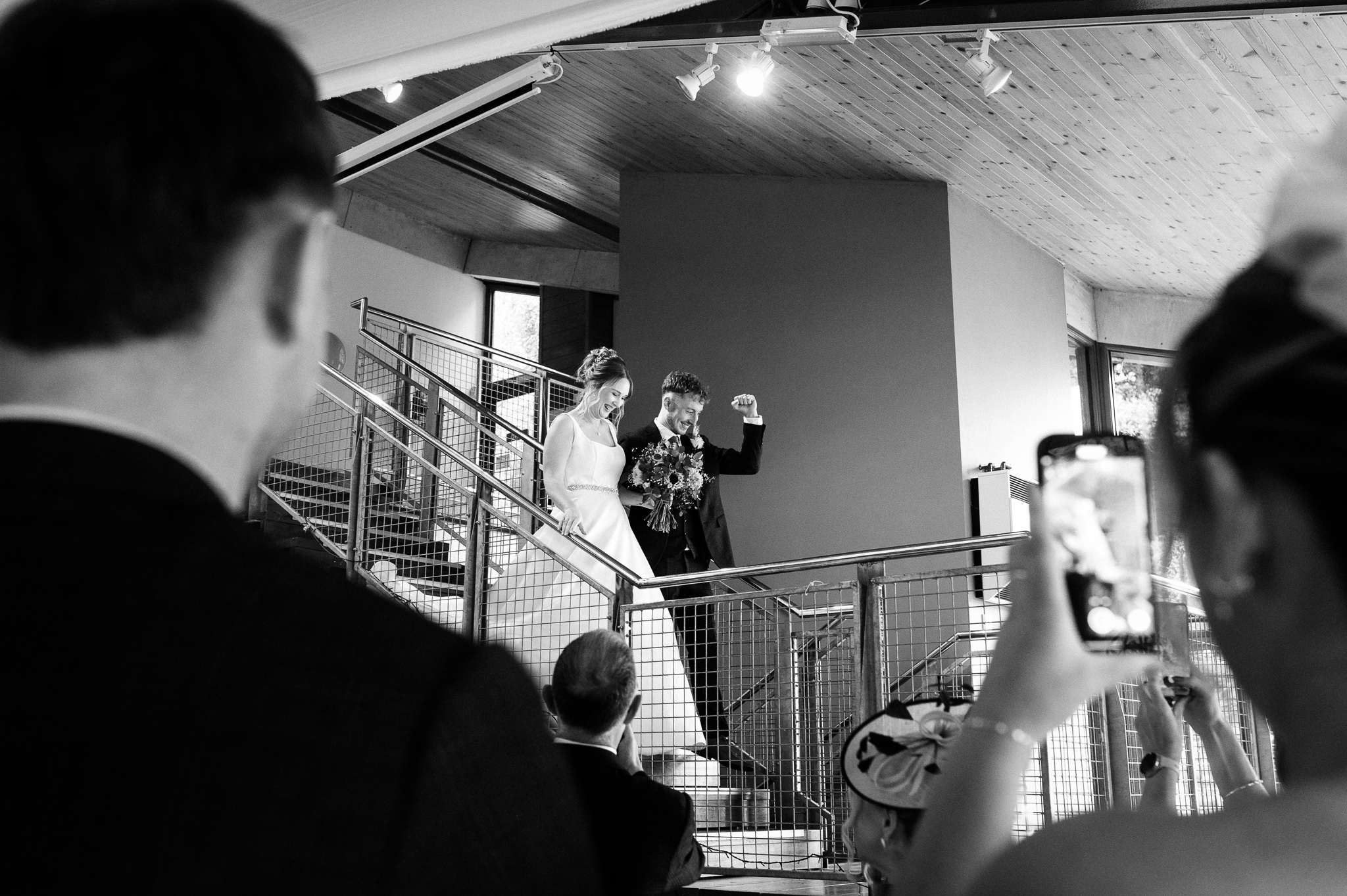 bride and groom making an entrance down a staircase into their wedding breakfast