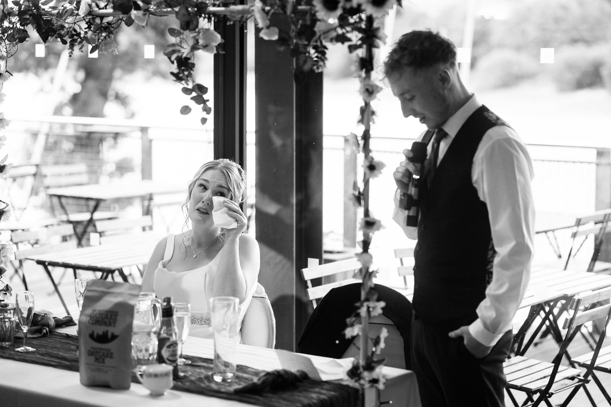 bride wiping her eye as her groom gives a speech