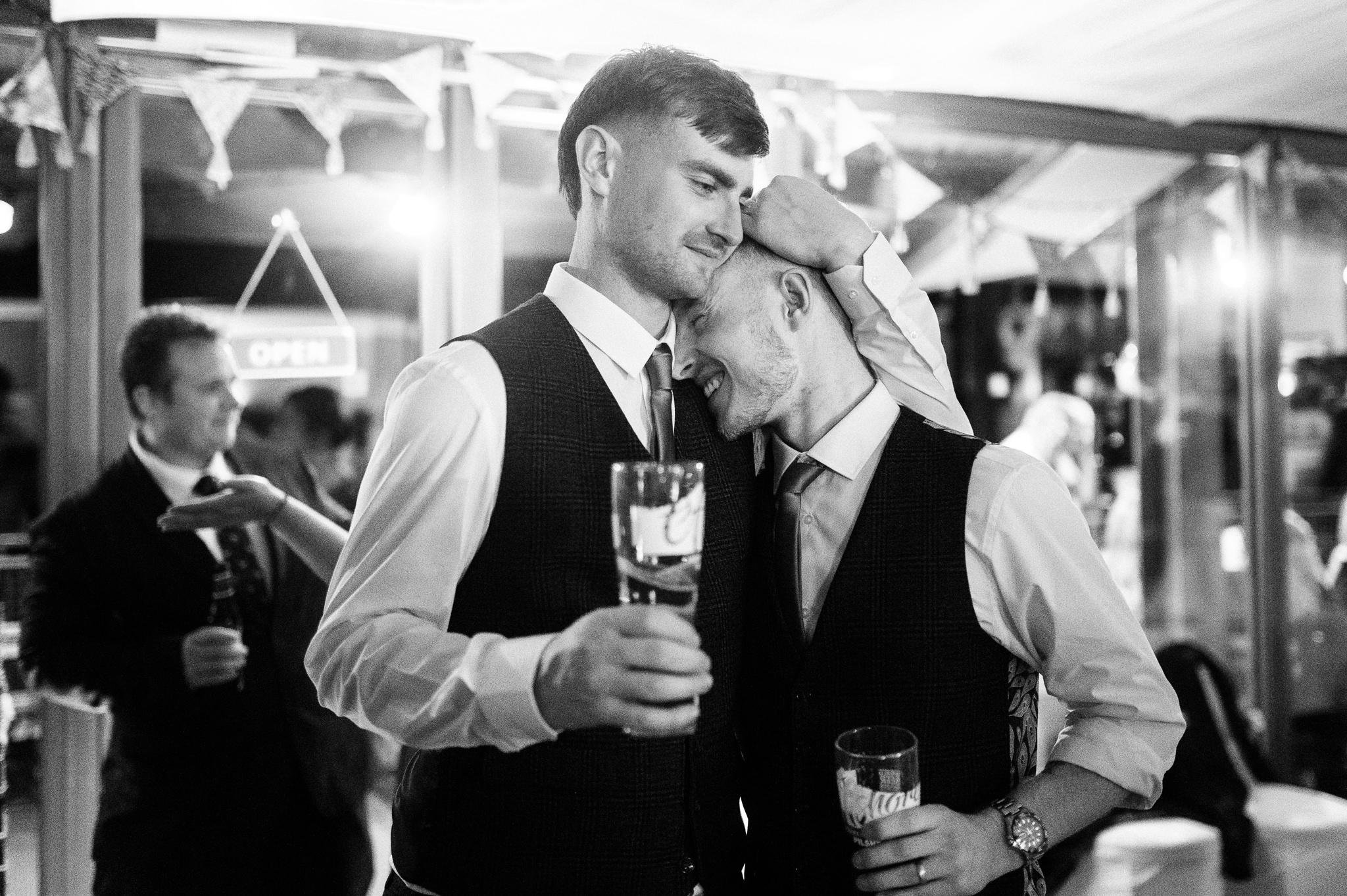 groom and his cousin holding beers and hugging