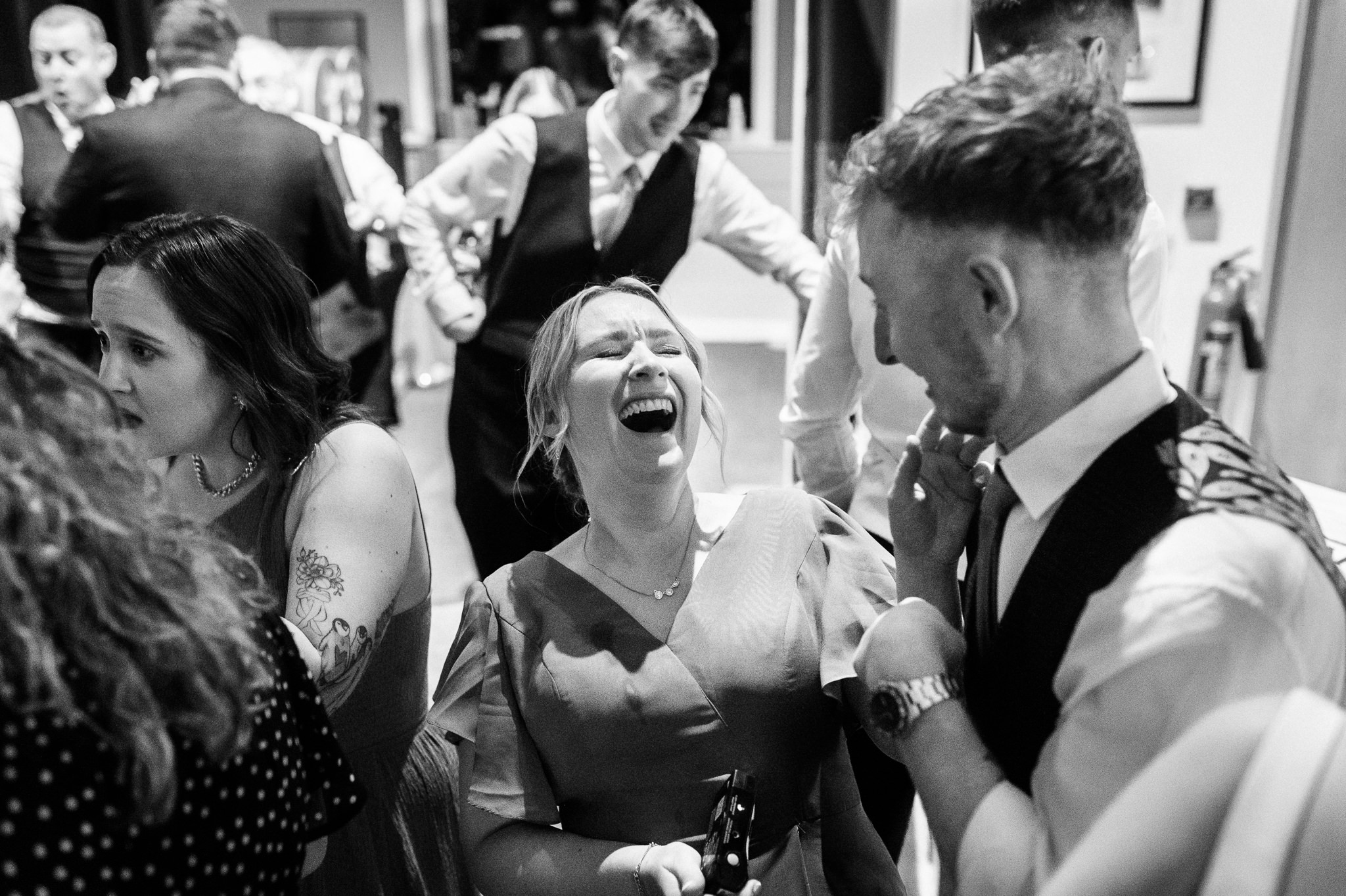 woman at a wedding reception tipping her head back and laughing