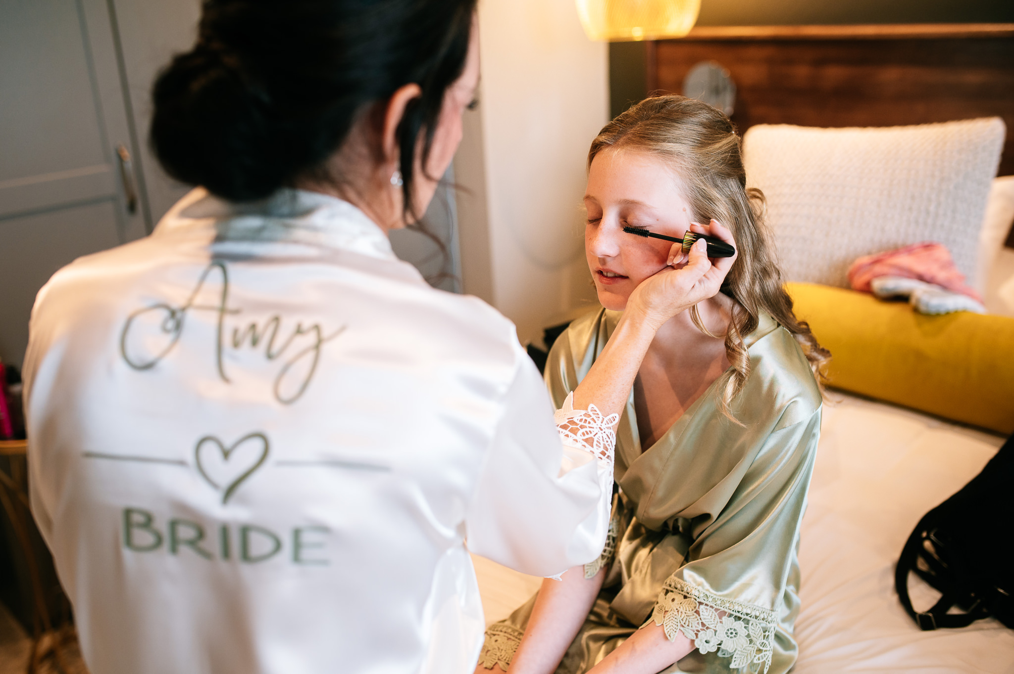 bride putting makeup on one of her daughters