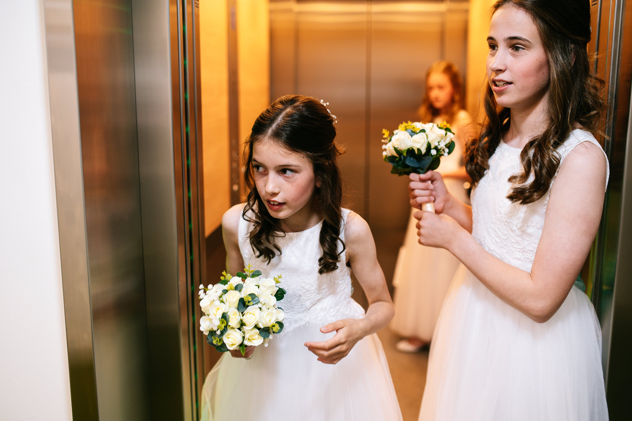 bridesmaids holding bouquets waiting for the lift doors to close