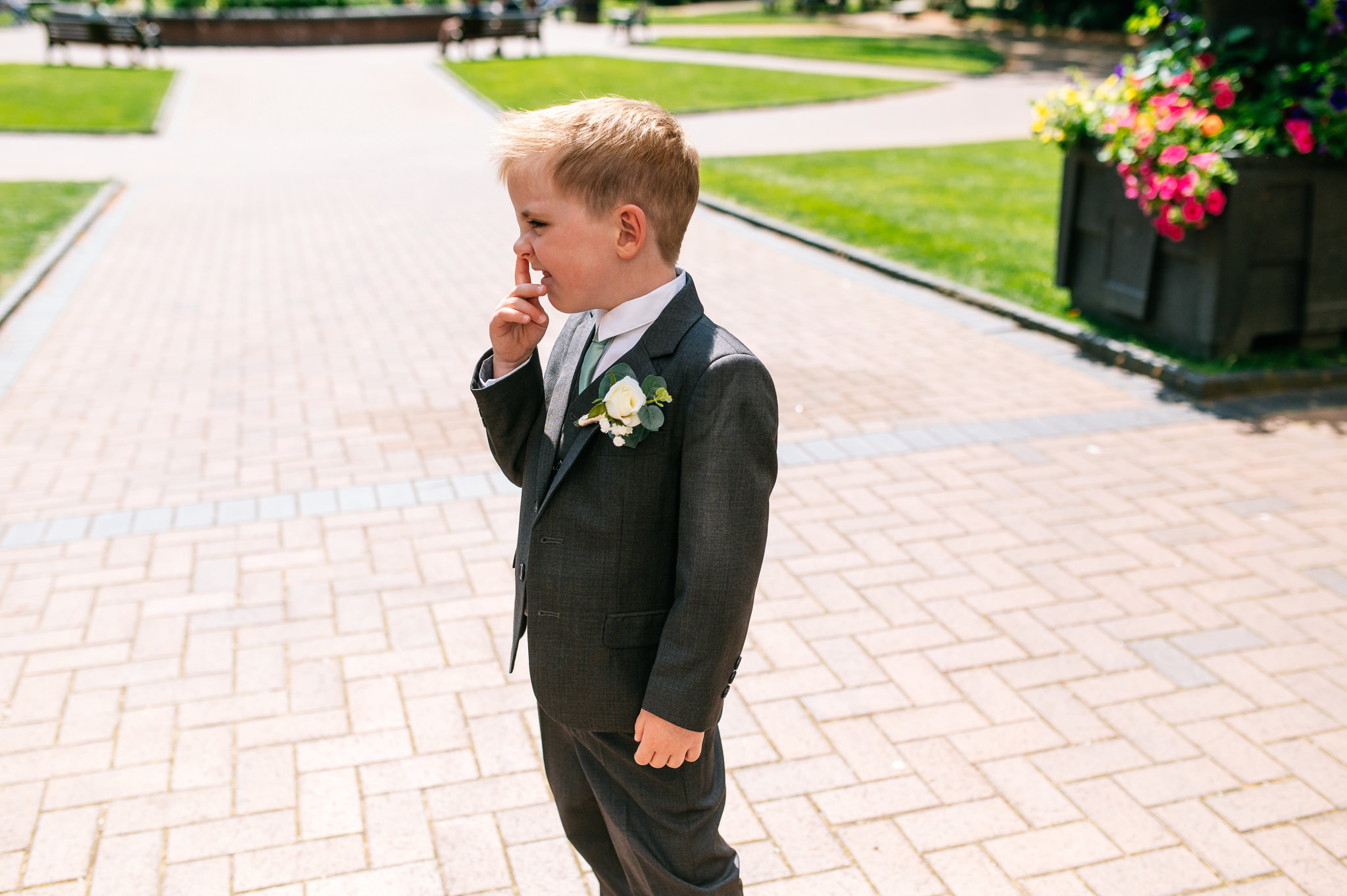 page boy stood outside picking his nose