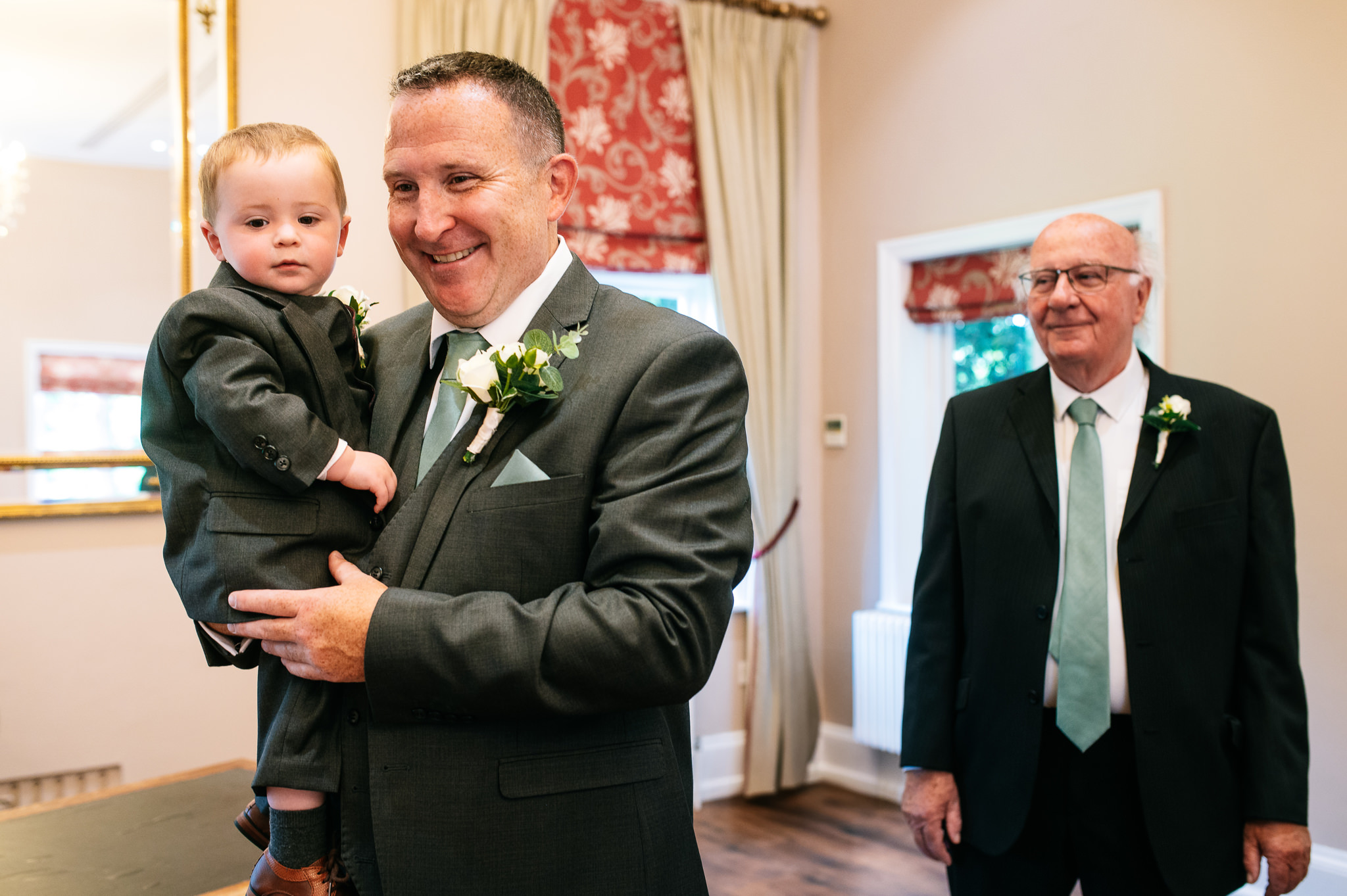 groom waiting in bridgford hall holding his young son