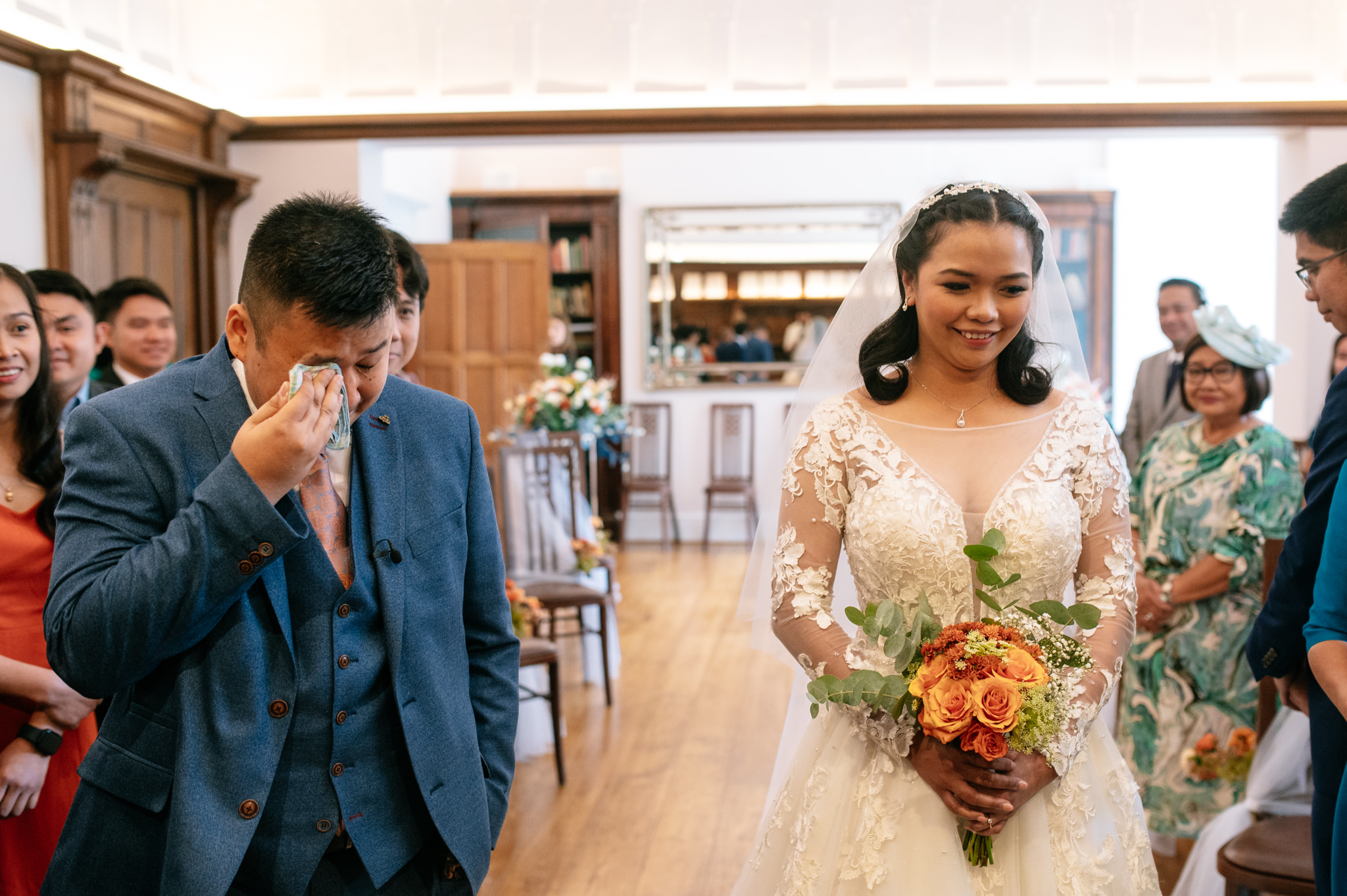 a groom wiping tears from his eyes after seeing his bride to be walk down the aisle. 